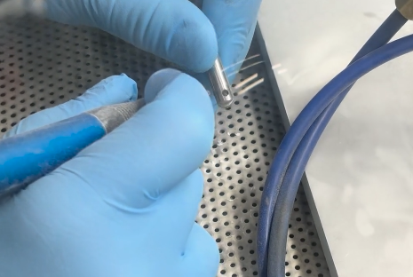 Sand Blasting Process on Metal Part Technician using sand blasting equipment to clean and finish a small metal component